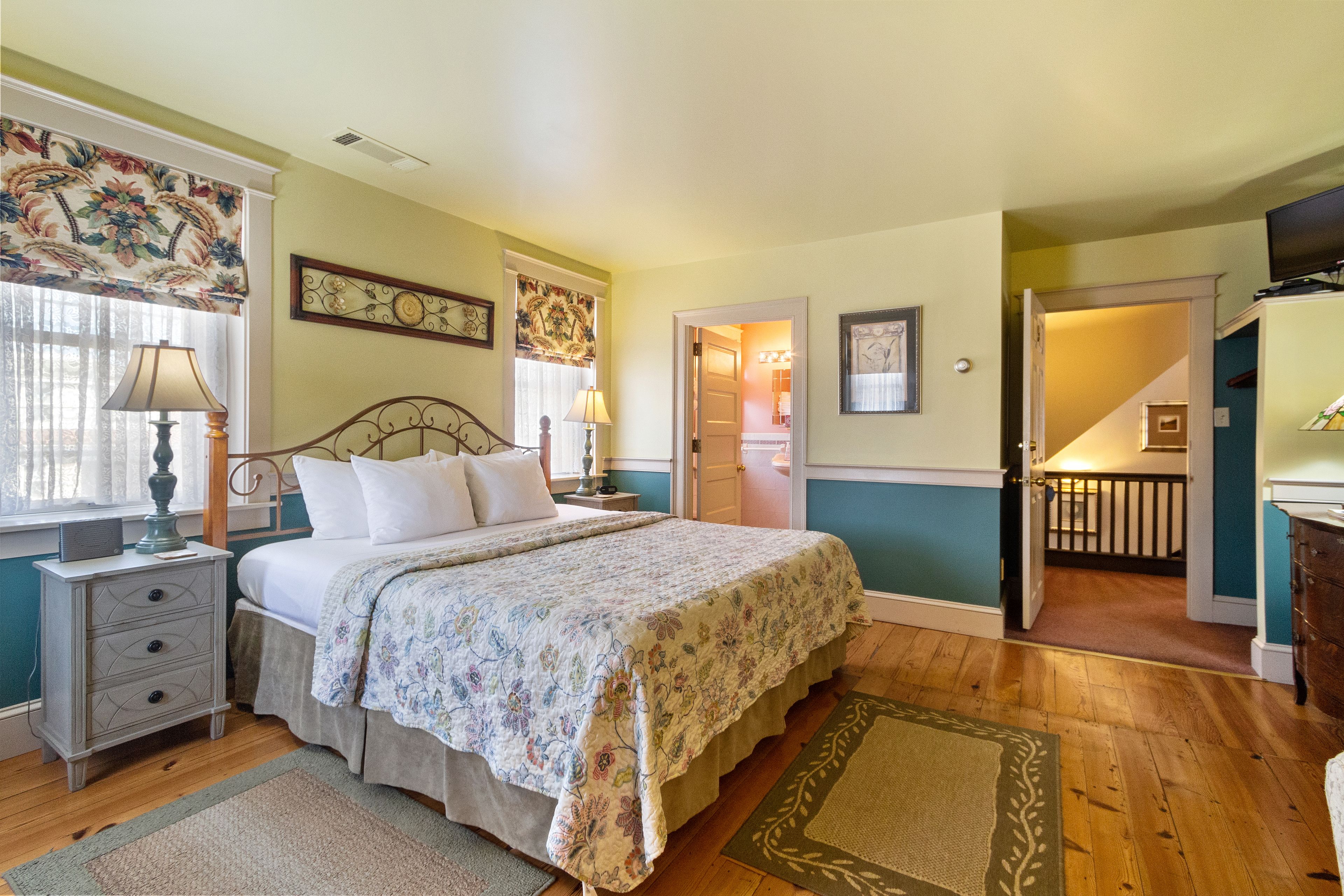 A bedroom with a bed, nightstands, a dresser, and a television.