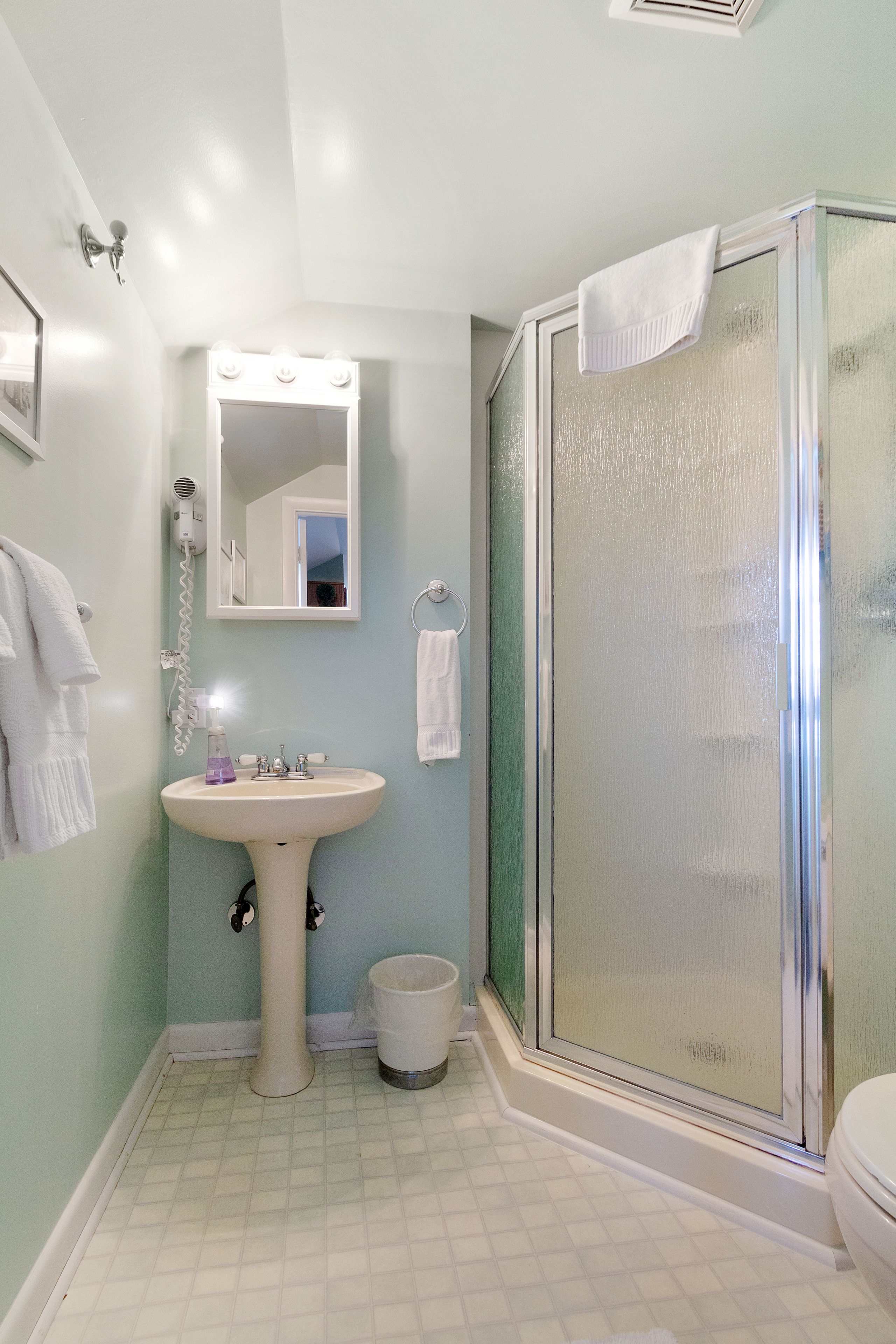 A bathroom with a sink, mirror, and shower.