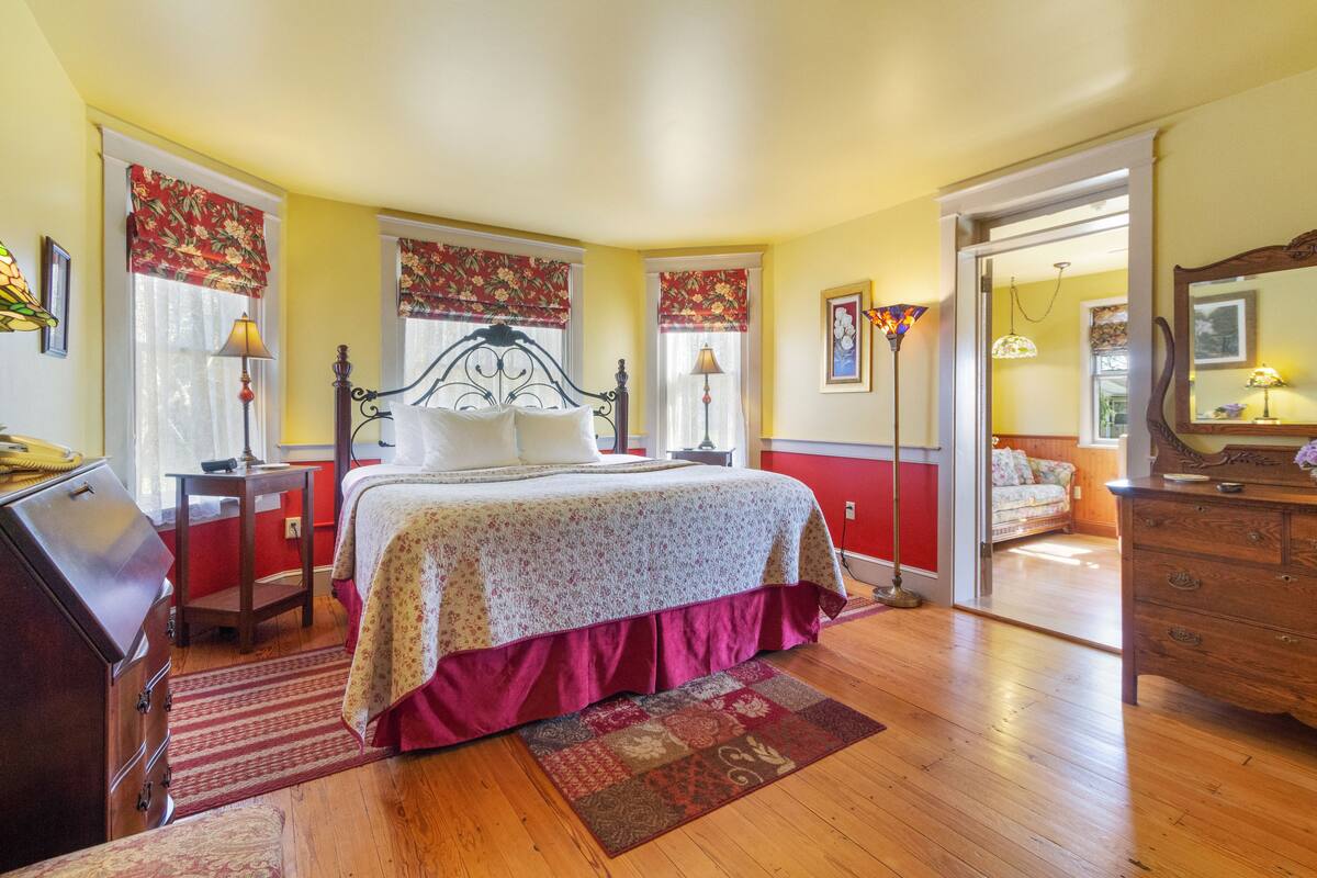 A bedroom with a bed, wooden dresser, and a nightstand.