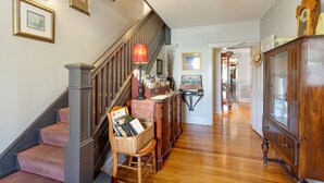 A staircase with a wooden handrail and carpeted steps, leading to a room with a wooden cabinet and a lamp. - After Eight Bed and Breakfast (Gordonville)
