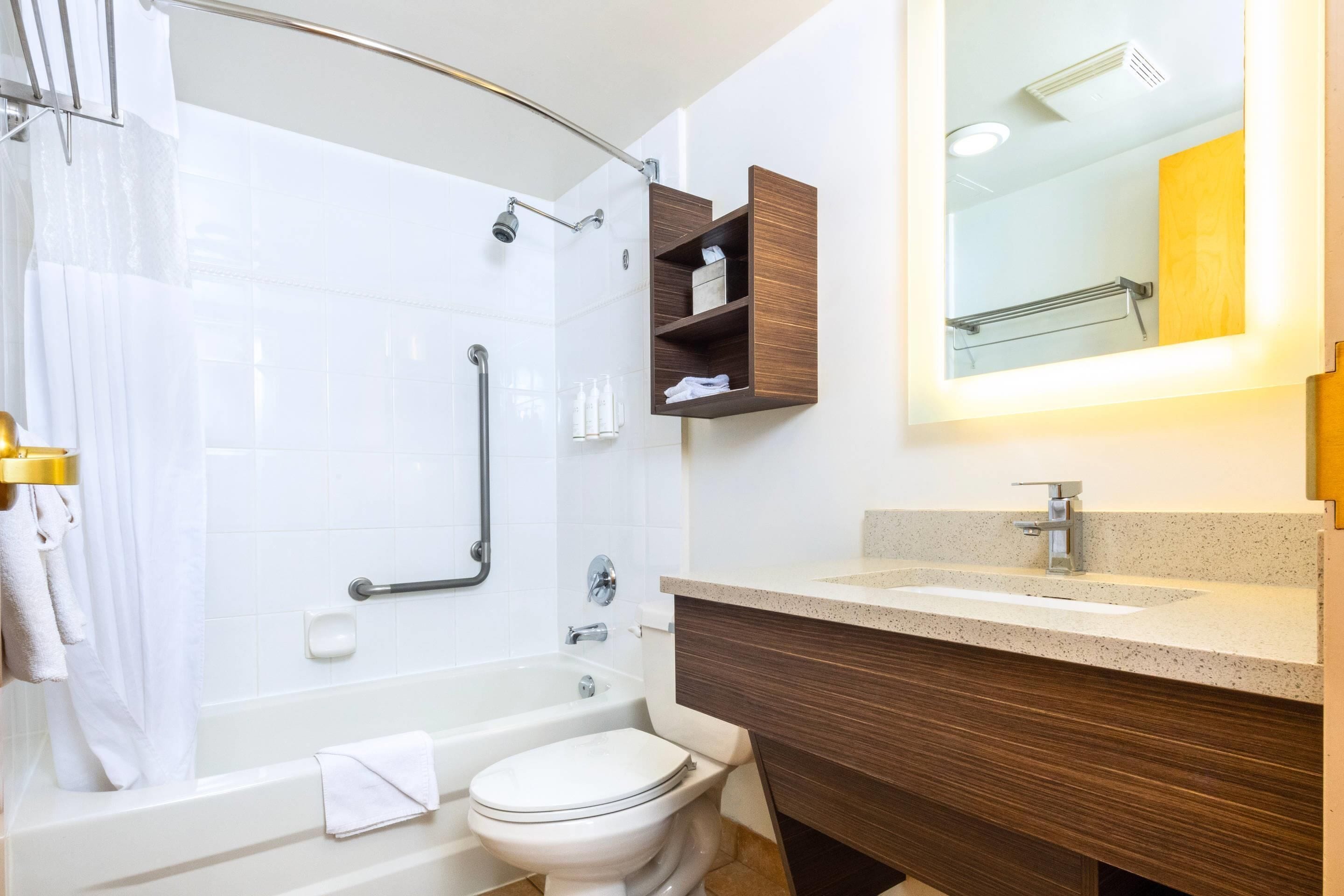 A modern bathroom with a bathtub, toilet, and vanity with a mirror.