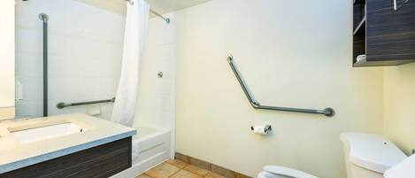 Ein modernes Badezimmer mit Badewanne, Toilette und Haltegriffen.
