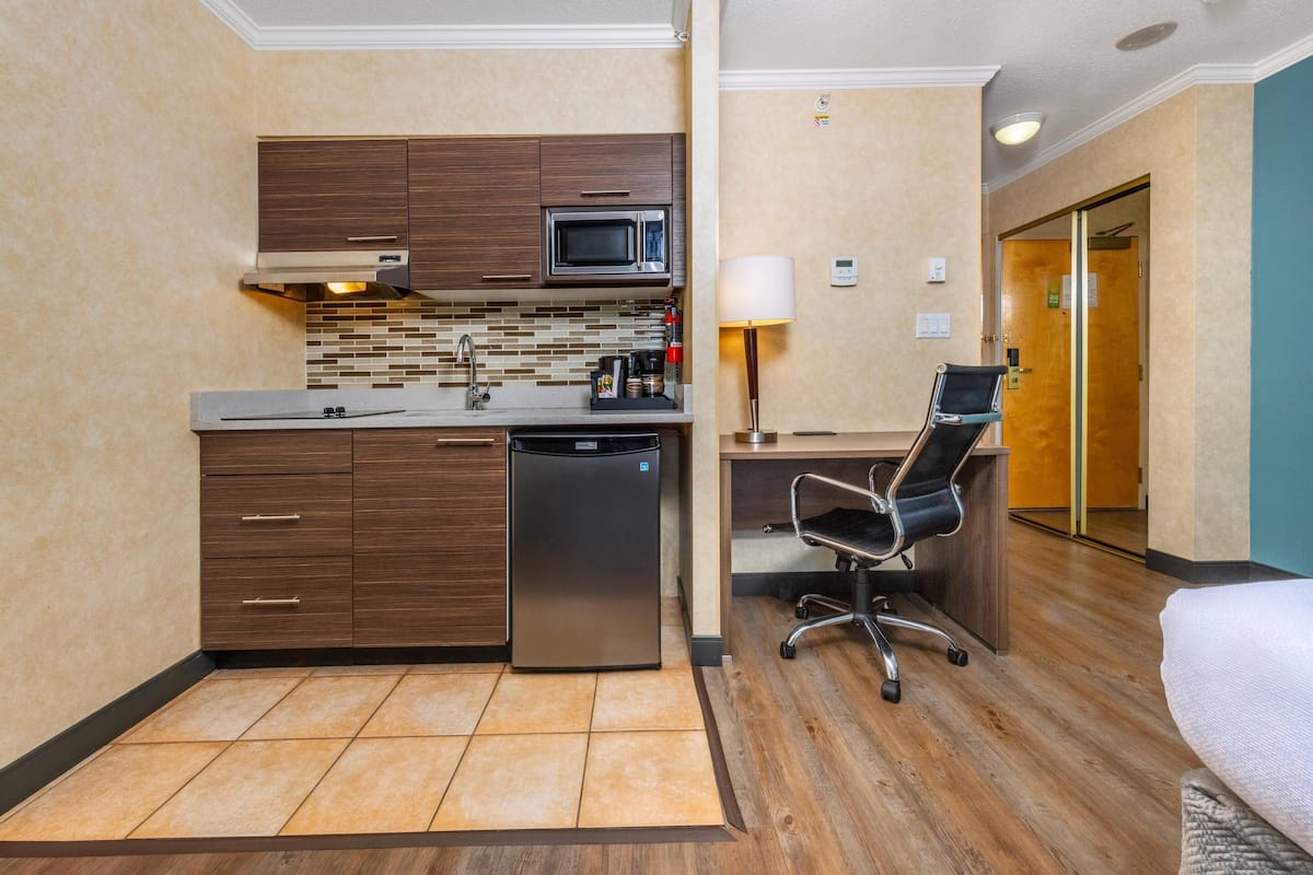 Une chambre d’hôtel compacte équipée d’une kitchenette, d’un bureau et d’une chaise.