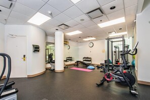 Un gimnasio con equipo de ejercicio, un reloj y una puerta.