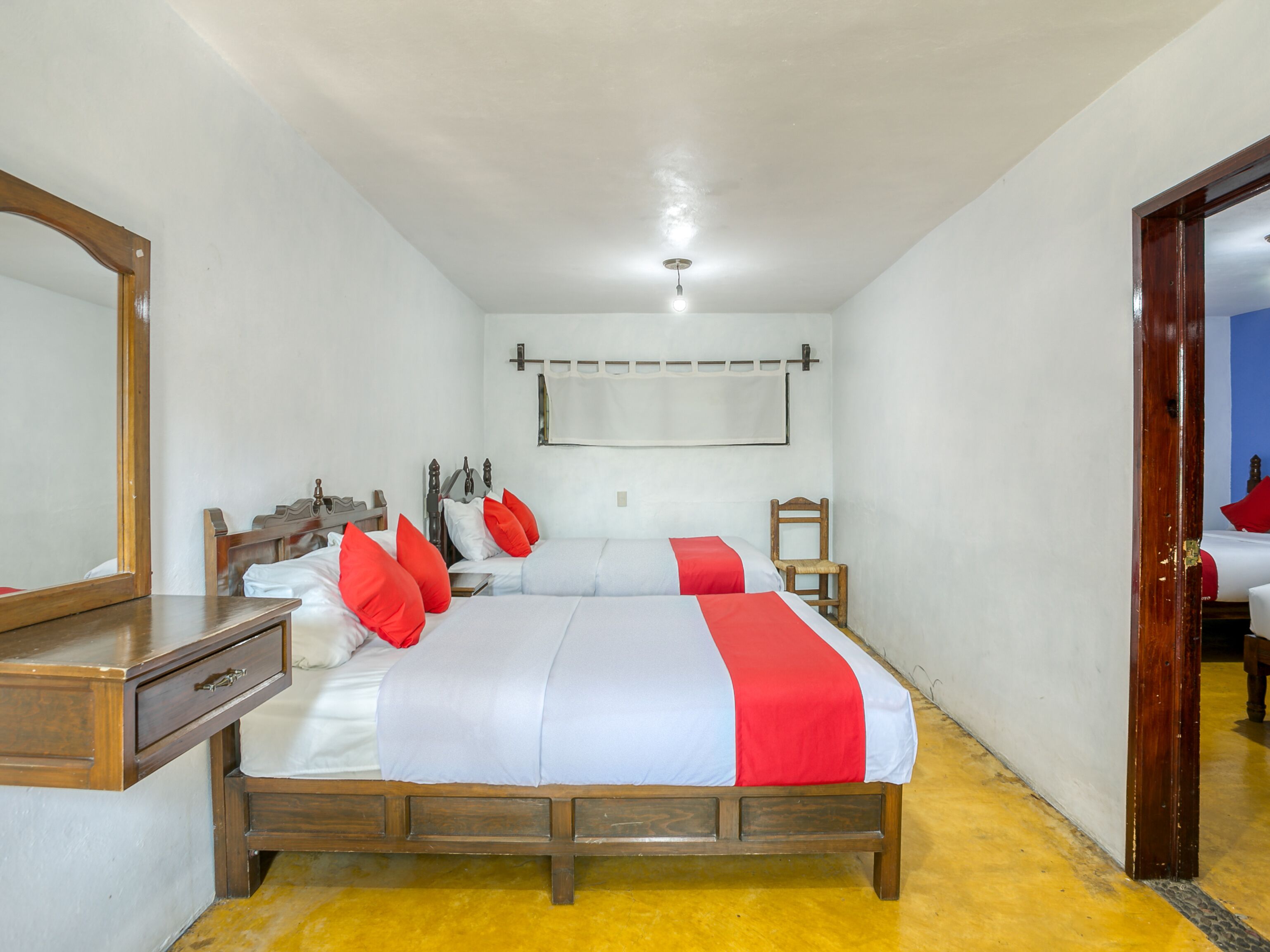 A bedroom with a wooden bed, a nightstand, a mirror, and a wooden chair.