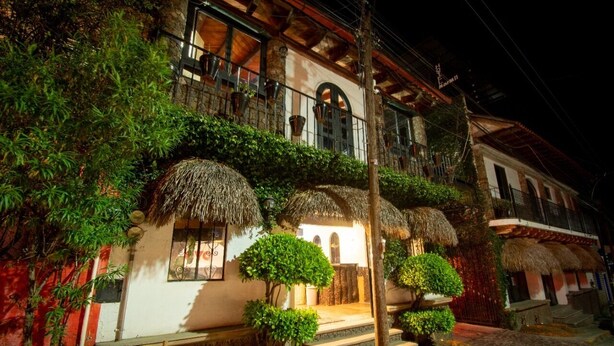 Un edificio tradicional con balcón, techos de paja y plantas en macetas.
