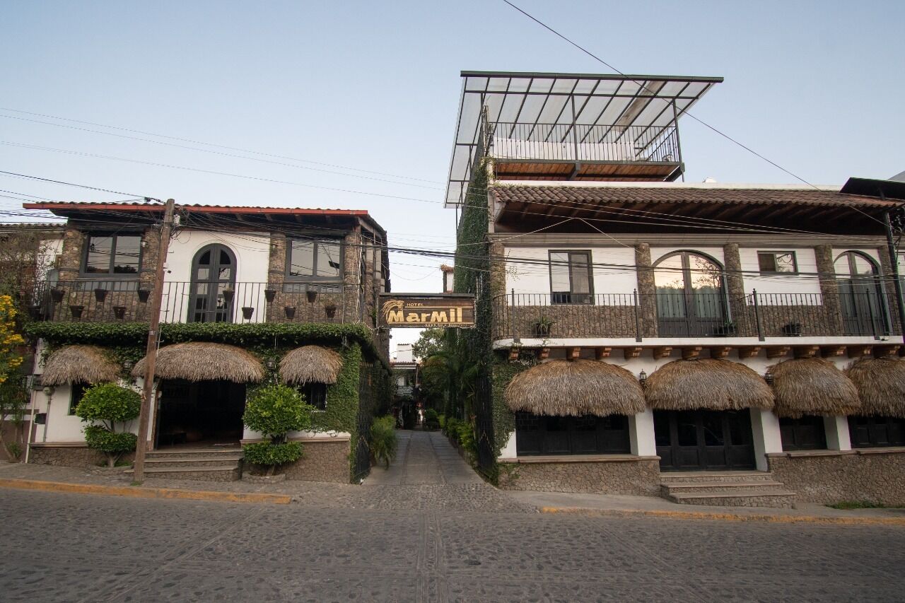 A hotel with a traditional architectural style, featuring arched windows and a balcony with a thatched roof.
