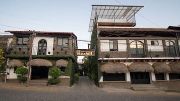 A hotel with a traditional architectural style, featuring arched windows and a balcony with a thatched roof.