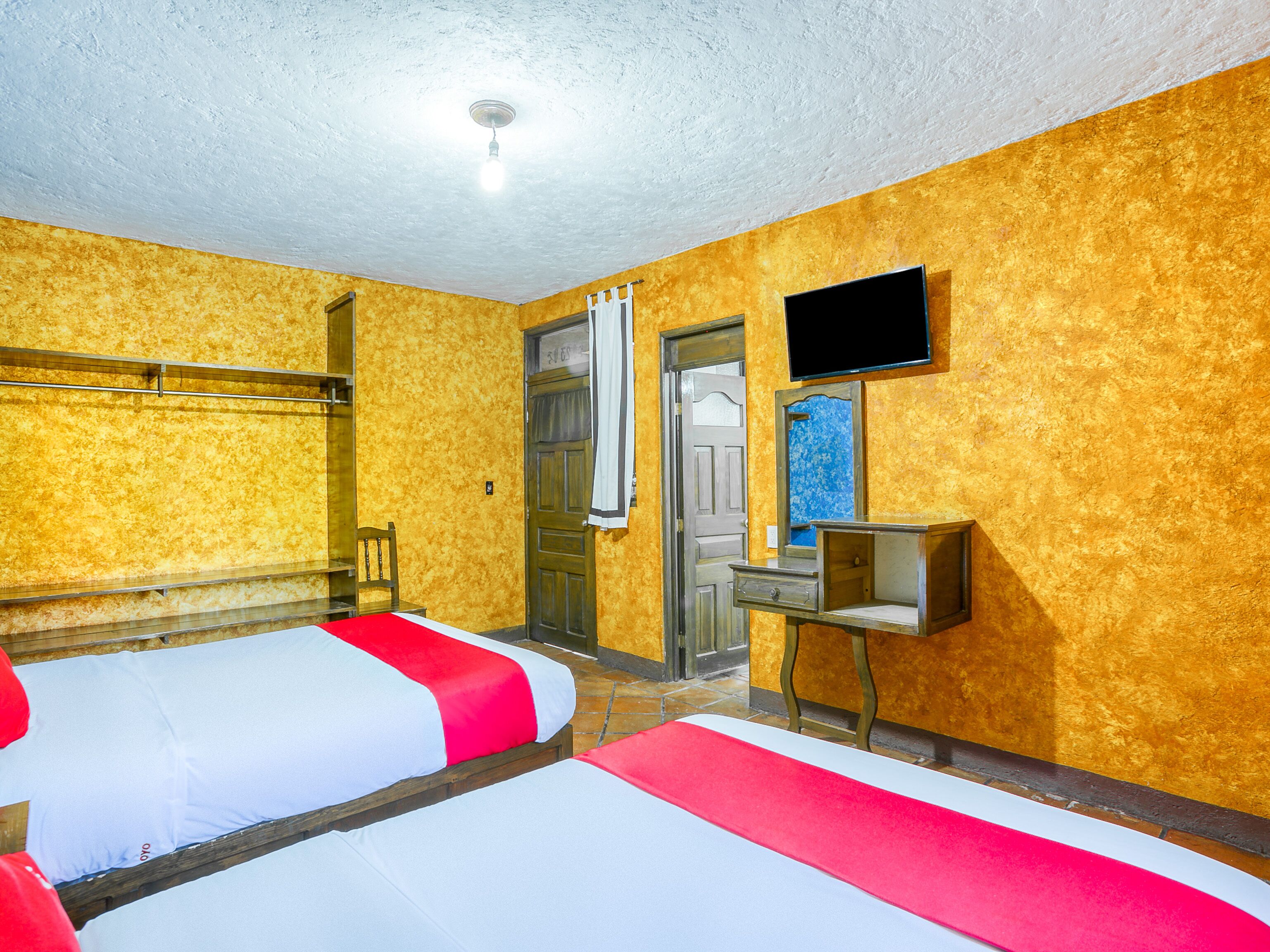 Una habitación de hotel con dos camas, televisión, espejo y puerta.