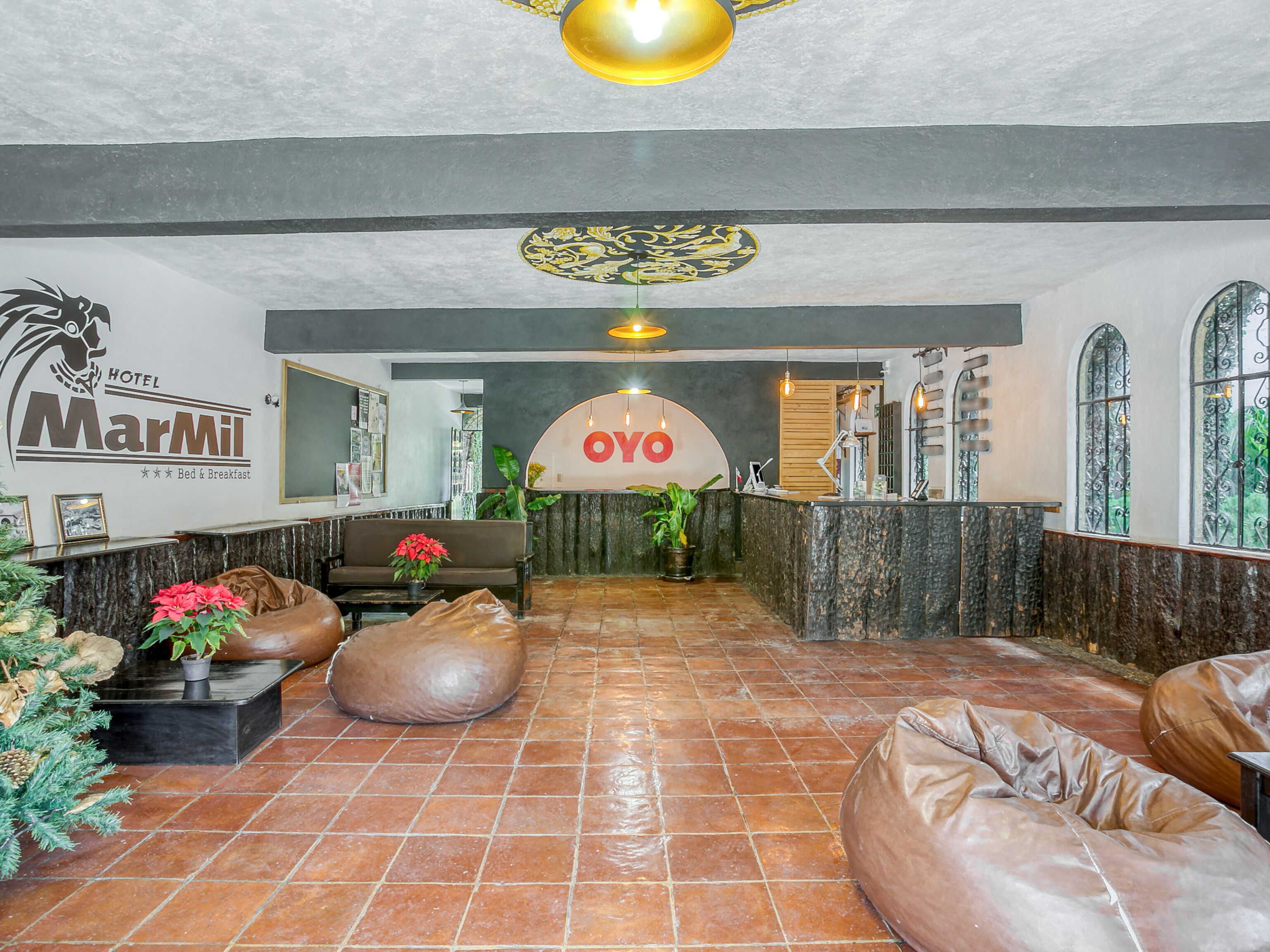 A hotel lobby with a reception desk, a sofa, a coffee table, and a potted plant.