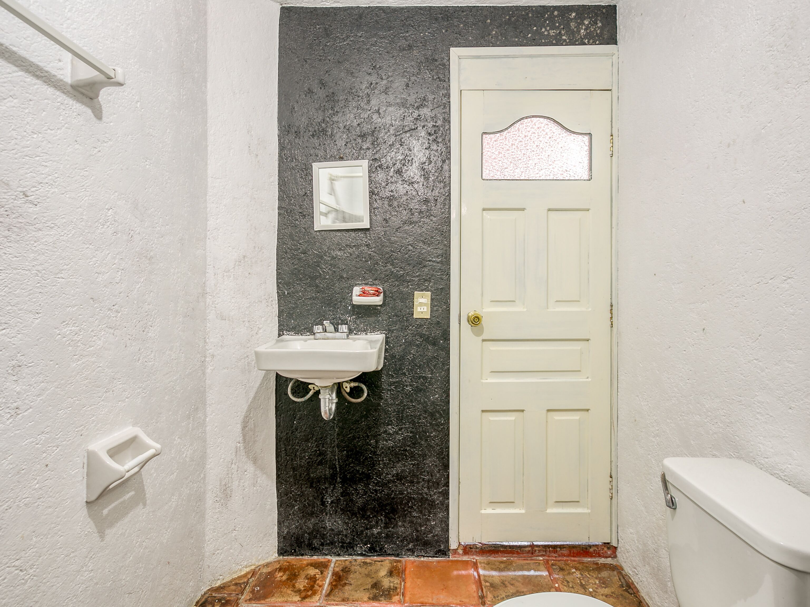 A bathroom with a white sink, a door, and a toilet.