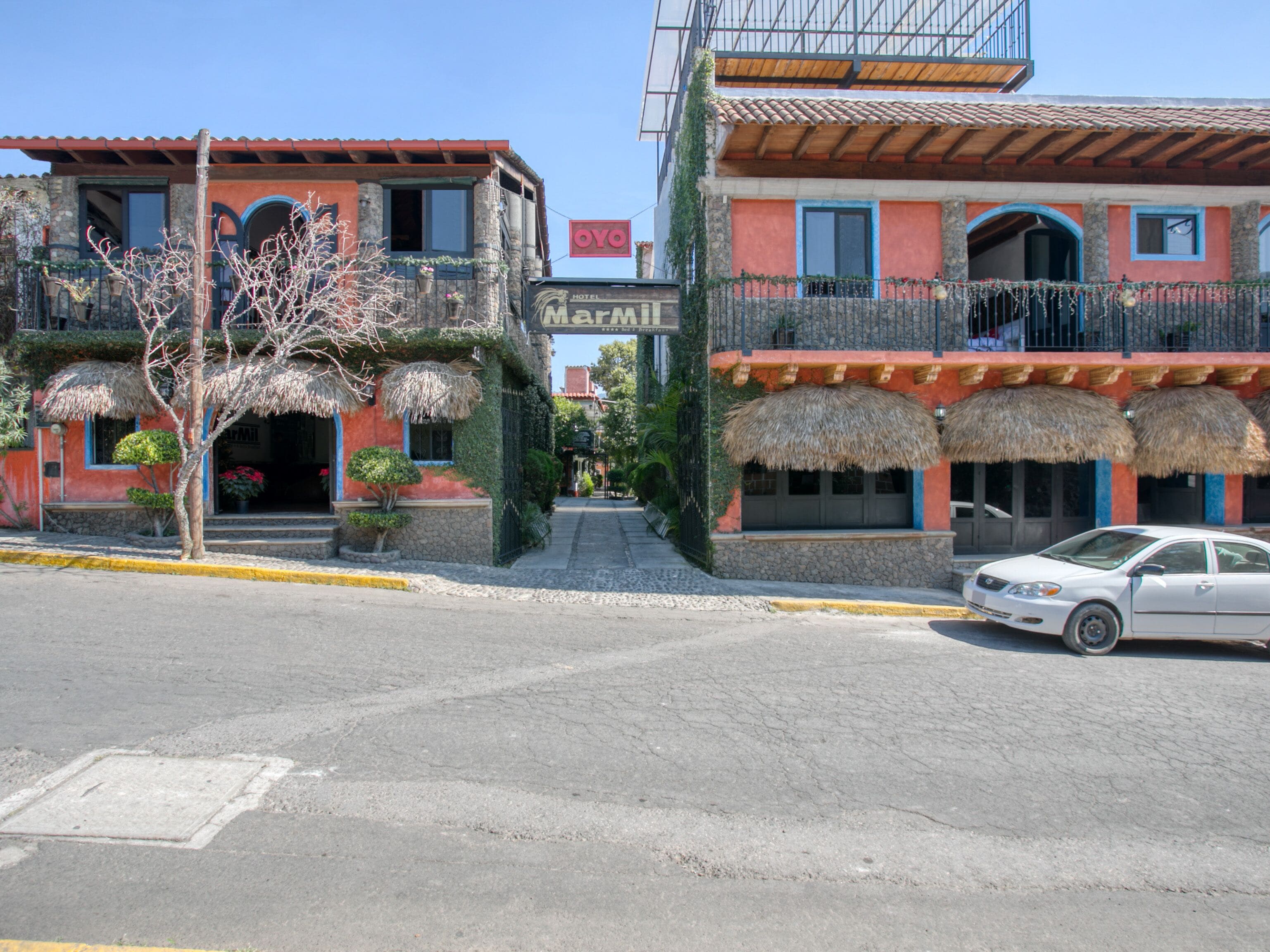 A hotel with a red facade, a balcony with a thatched roof, and a sign indicating it is a hotel.