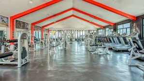 Un gimnasio espacioso con cintas de correr, máquinas de pesas y pesas libres.