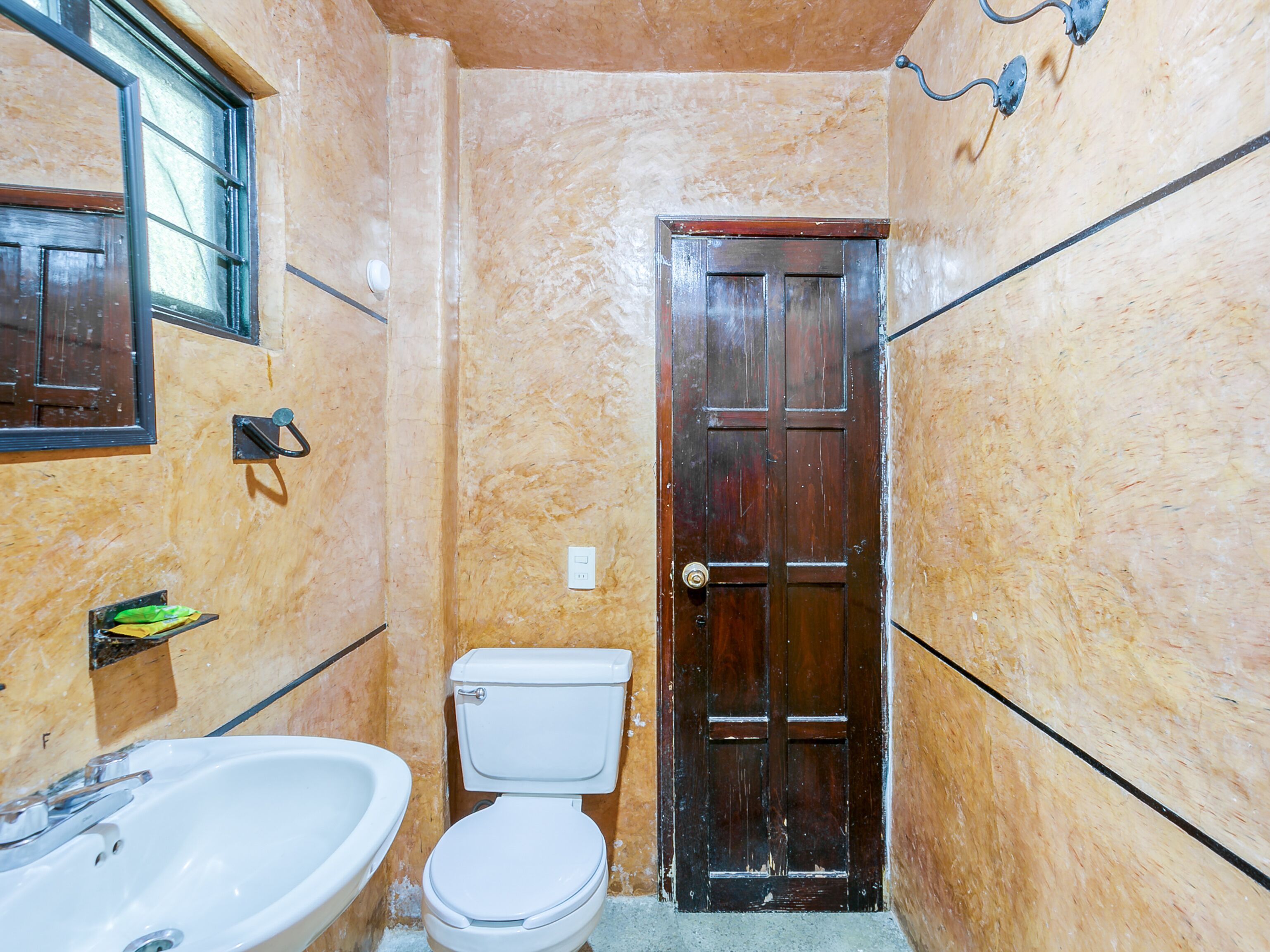 A bathroom with a toilet, sink, and wooden door.