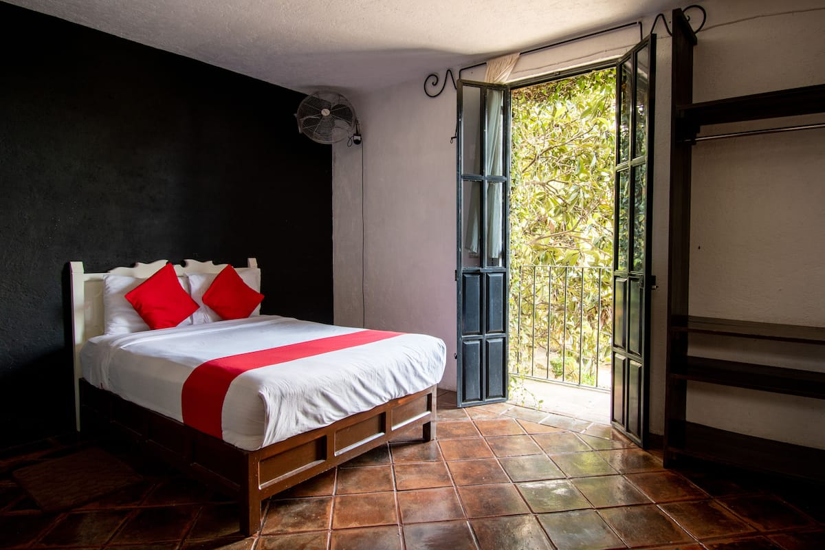 Ein Schlafzimmer mit Bett, Ventilator, Fenster und Tür.