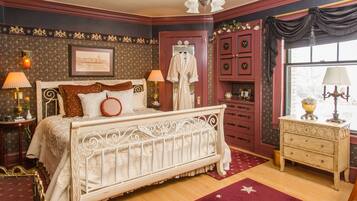 Een klassieke slaapkamer met een hemelbed, een nachtkastje met lamp, een dressoir en een raam met gordijnen.