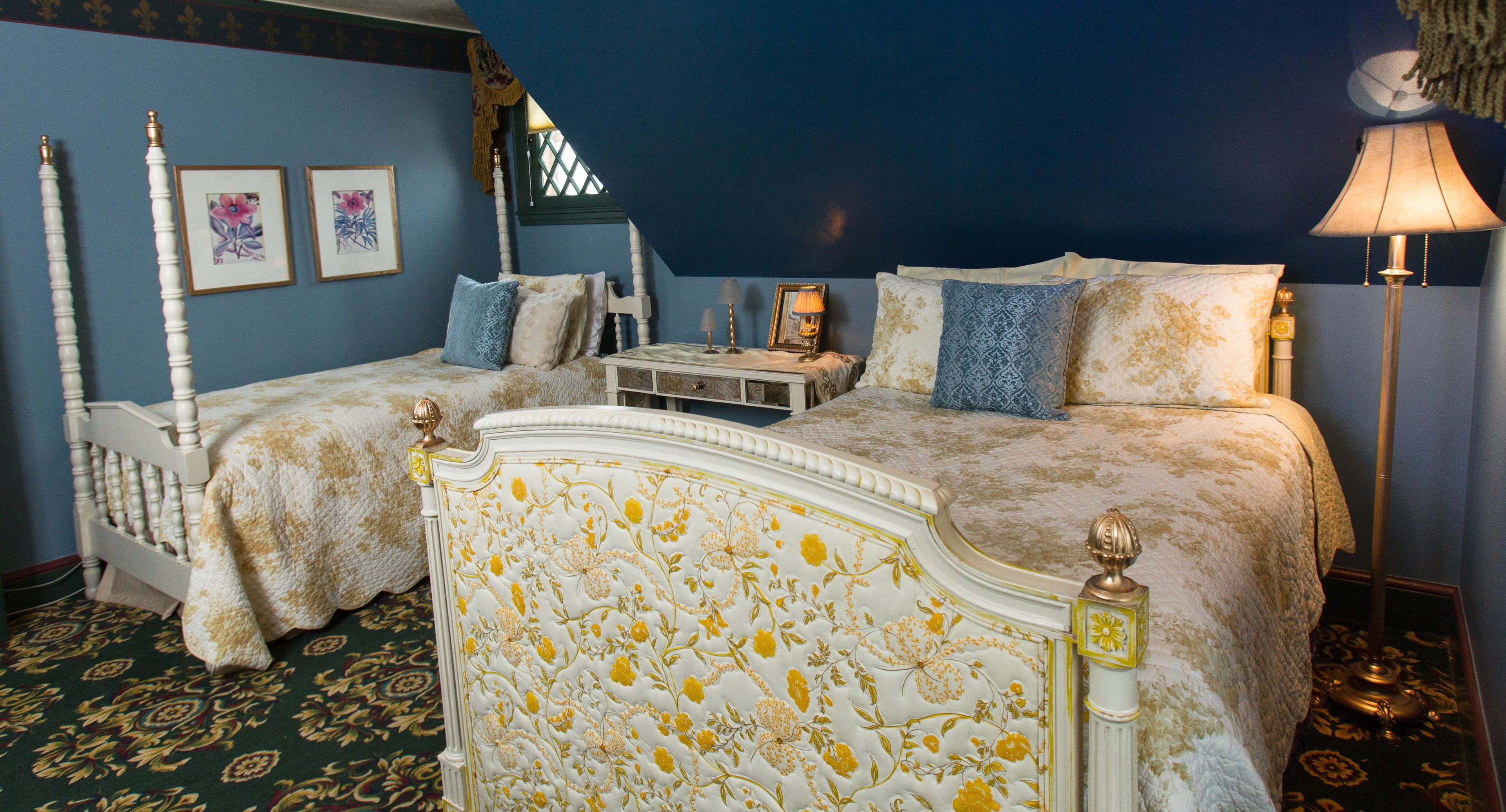 A bedroom with two beds, a nightstand, a lamp, and framed artwork on the wall.