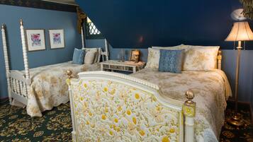 A bedroom with two beds, a nightstand, a lamp, and framed artwork on the wall.