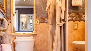 A bathroom with a toilet, sink, and a mirror with a chandelier.