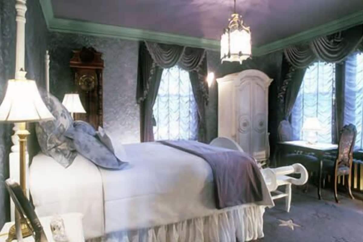 A bedroom with a large bed, a wardrobe, and a chair.