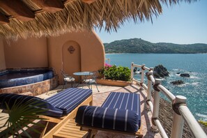 A terrace with two striped lounge chairs, a small table, and a hot tub. - Villa El Murmullo by La Casa Que Canta (Zihuatanejo)