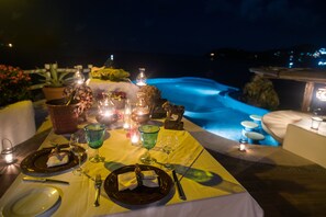 An outdoor dining setup with a table set for two, featuring plates, cutlery, and glasses. A small fountain and potted plants are visible in the background. - Villa El Murmullo by La Casa Que Canta (Zihuatanejo)
