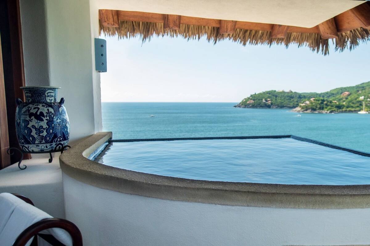 A circular infinity pool with a clear view of the sea and a small island in the distance.