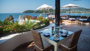 Un área de comedor al aire libre con una mesa lista para dos personas, con vista al mar.