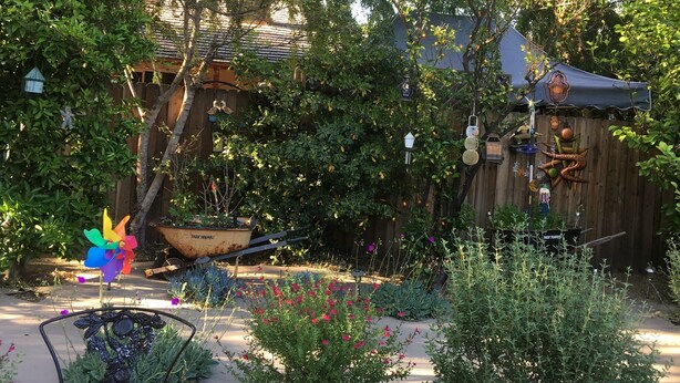 A garden with a chair, a pinwheel, and a wooden fence. - Sunshine LA BnB (Van Nuys)