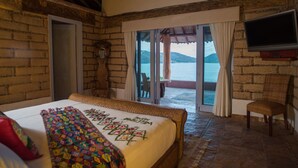 A bedroom with a bed, a chair, a TV, and a view of the sea. - Villa El Ensueño by La Casa Que Canta (Zihuatanejo)