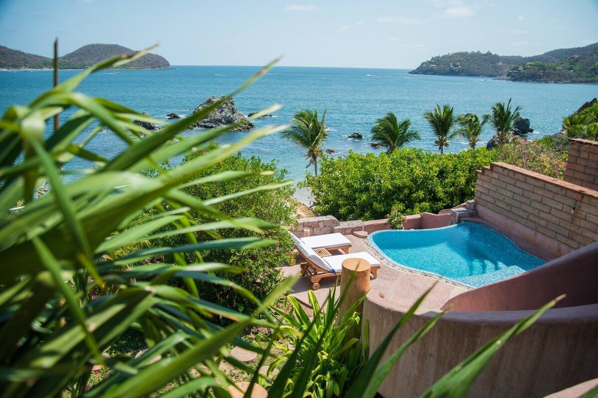 Ein privater Pool mit Meerblick, umgeben von üppiger Vegetation und einer Hügelslandschaft.