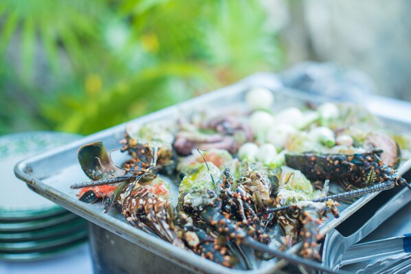 A tray of cooked seafood, including lobsters and crabs, on a metal serving dish.