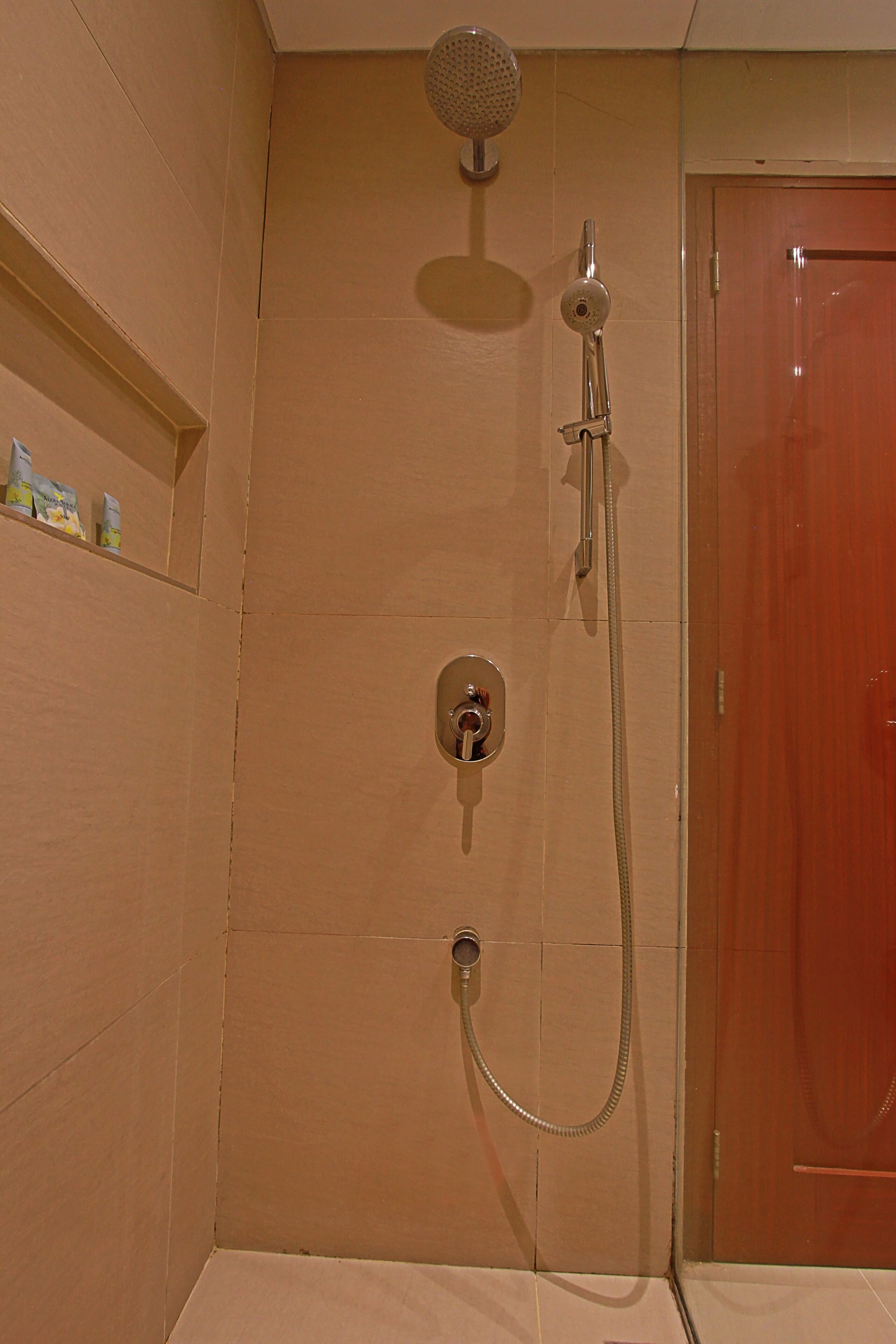 Une douche équipée d’un pommeau de douche à main et d’un robinet fixé au mur.