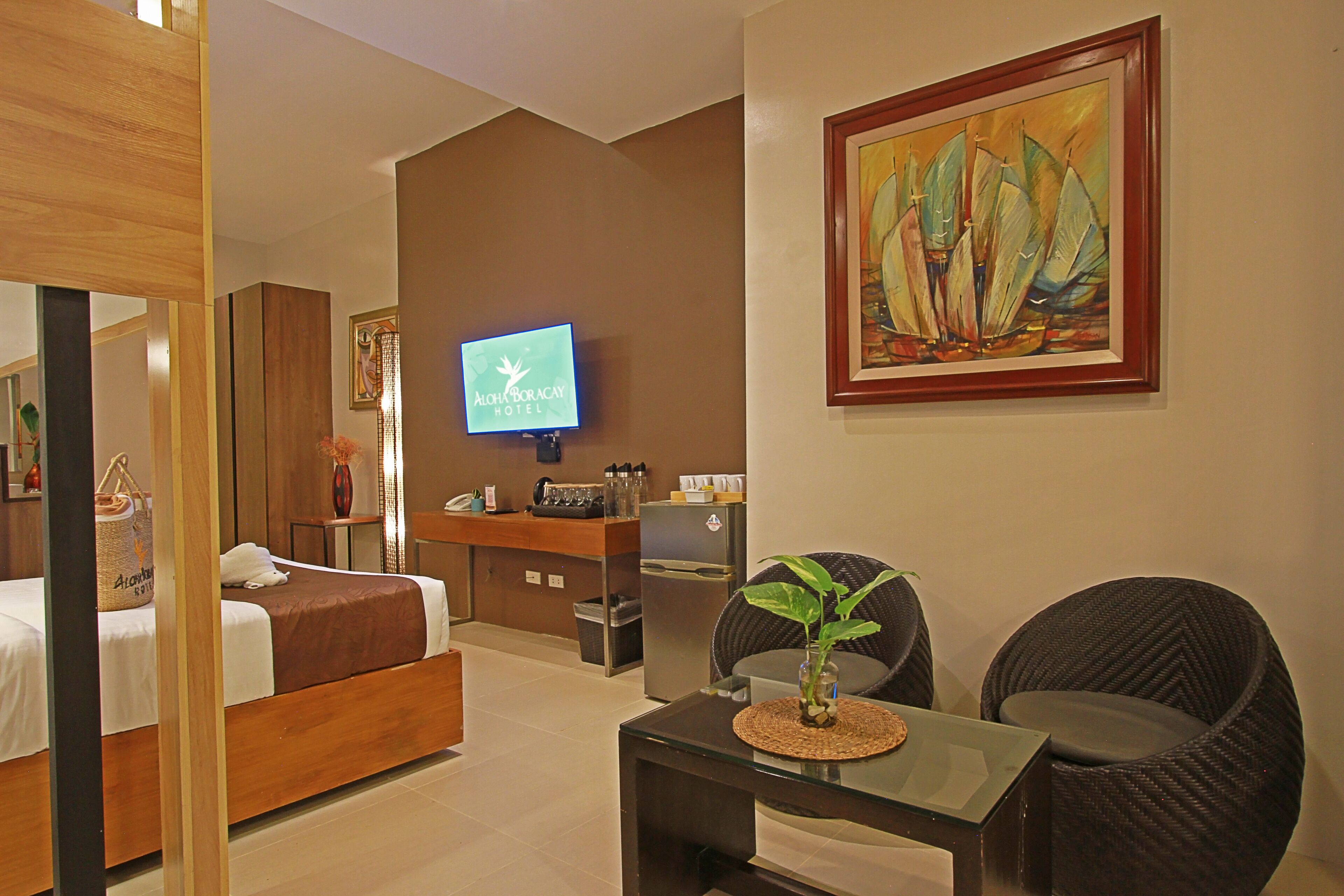 Ein Hotelzimmer mit einem Bett, einem Schreibtisch mit Computer, einem Fernseher und einem Gemälde.
