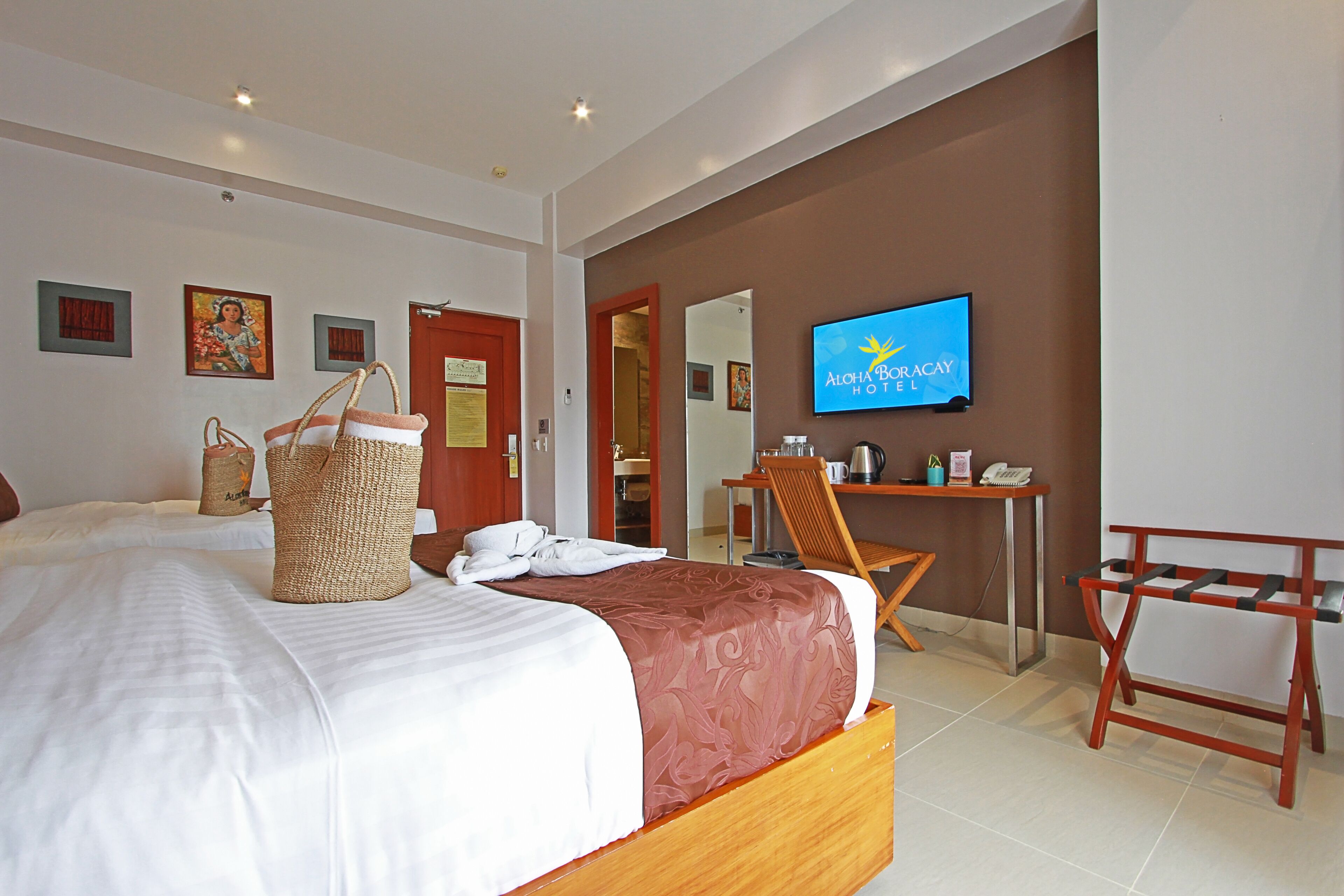 A hotel room with a bed, a desk, a chair, a television, and a wall-mounted sign.