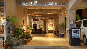 La entrada del hotel Aloha Boracay, con un mostrador de recepción, plantas en macetas y un cartel que indica la entrada.