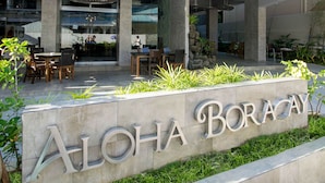 Exterior del hotel Aloha Boracay, con un cartel, zona de estar al aire libre y un diseño arquitectónico moderno.