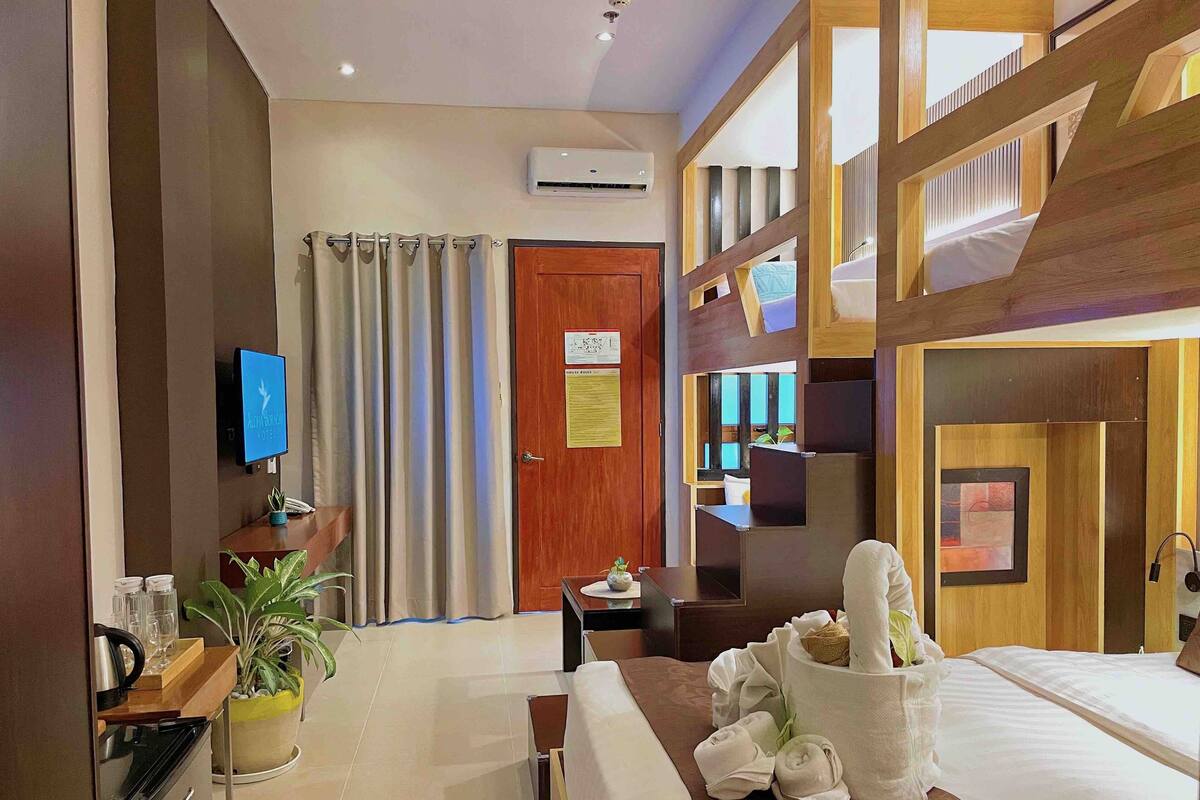 A hotel room with a bed, a desk, a TV, a bathroom, and a balcony.