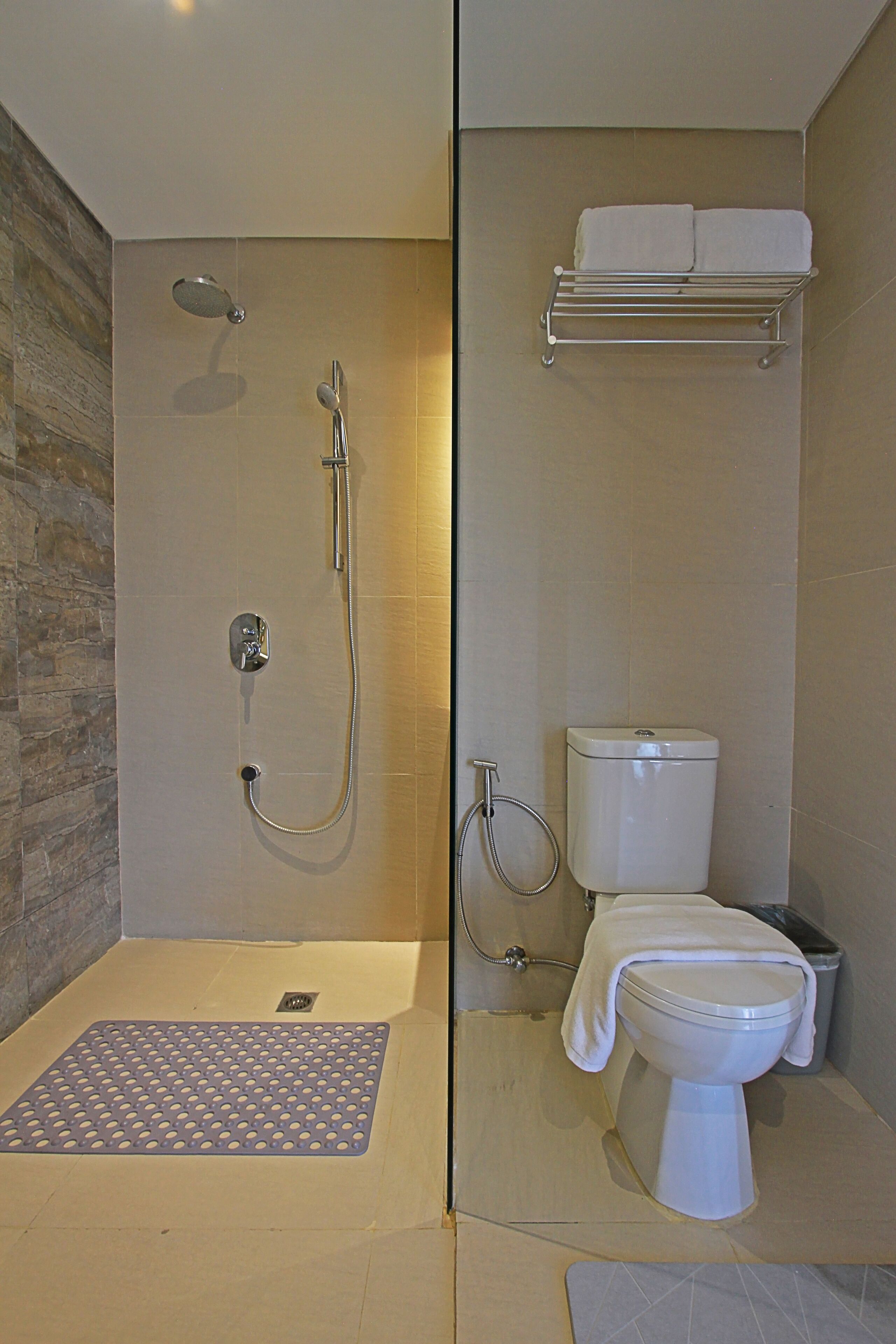 Et badeværelse med brusebad, toilet og håndklædeholder.