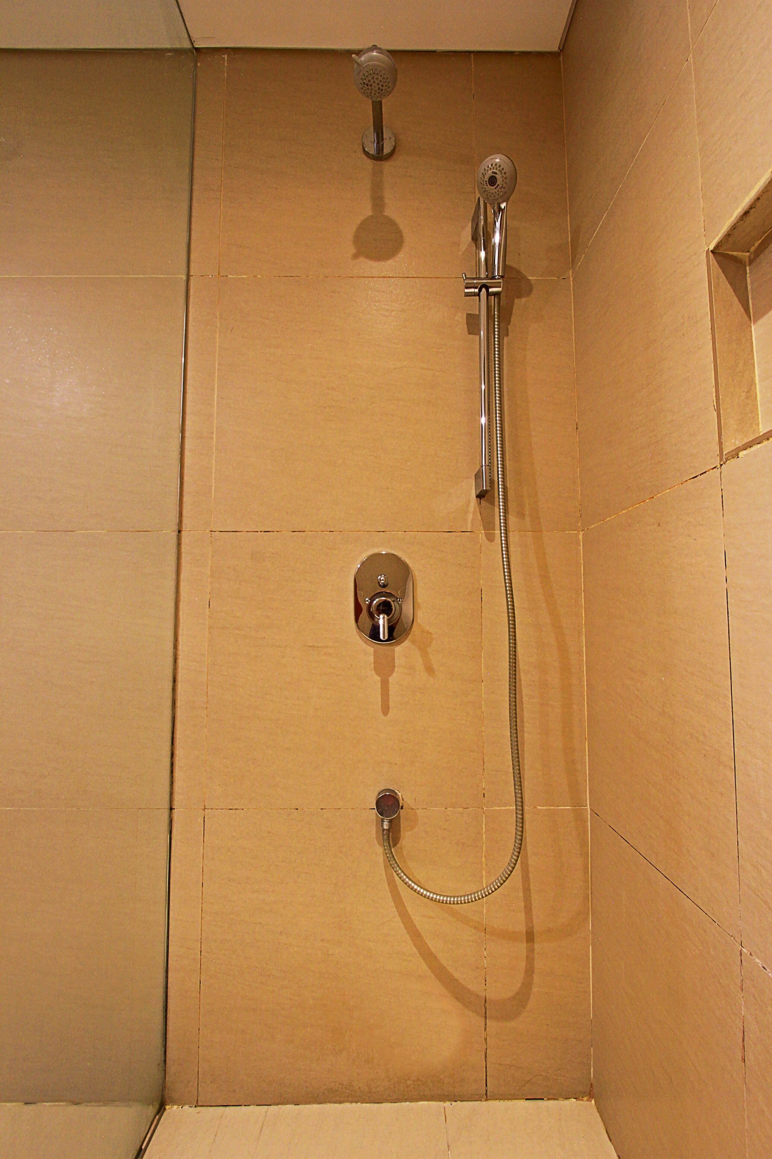 A shower with a handheld showerhead and a wall-mounted faucet.