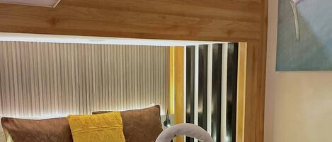 A hotel room with a bunk bed, a bedside table with towels and a basket of toiletries, and a painting on the wall.