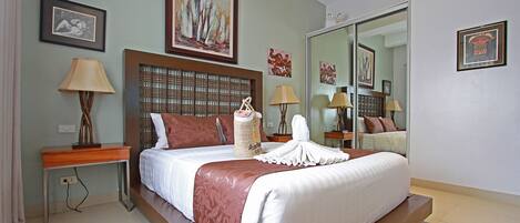 Una habitación de hotel moderna con una cama grande, un cabecero de madera, una mesita de noche con una lámpara y un espejo amplio.