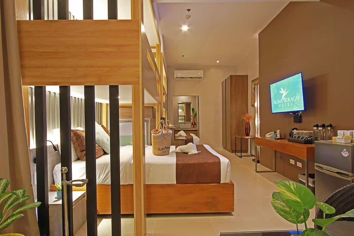 A hotel room with a bed, a desk, a television, and a bathroom visible through a partition.
