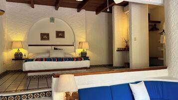 A bedroom with a bed, two bedside lamps, a ceiling fan, and a blue sofa.