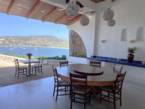 Un comedor con vistas al mar, sillas de madera, una mesa redonda y detalles decorativos en la pared.