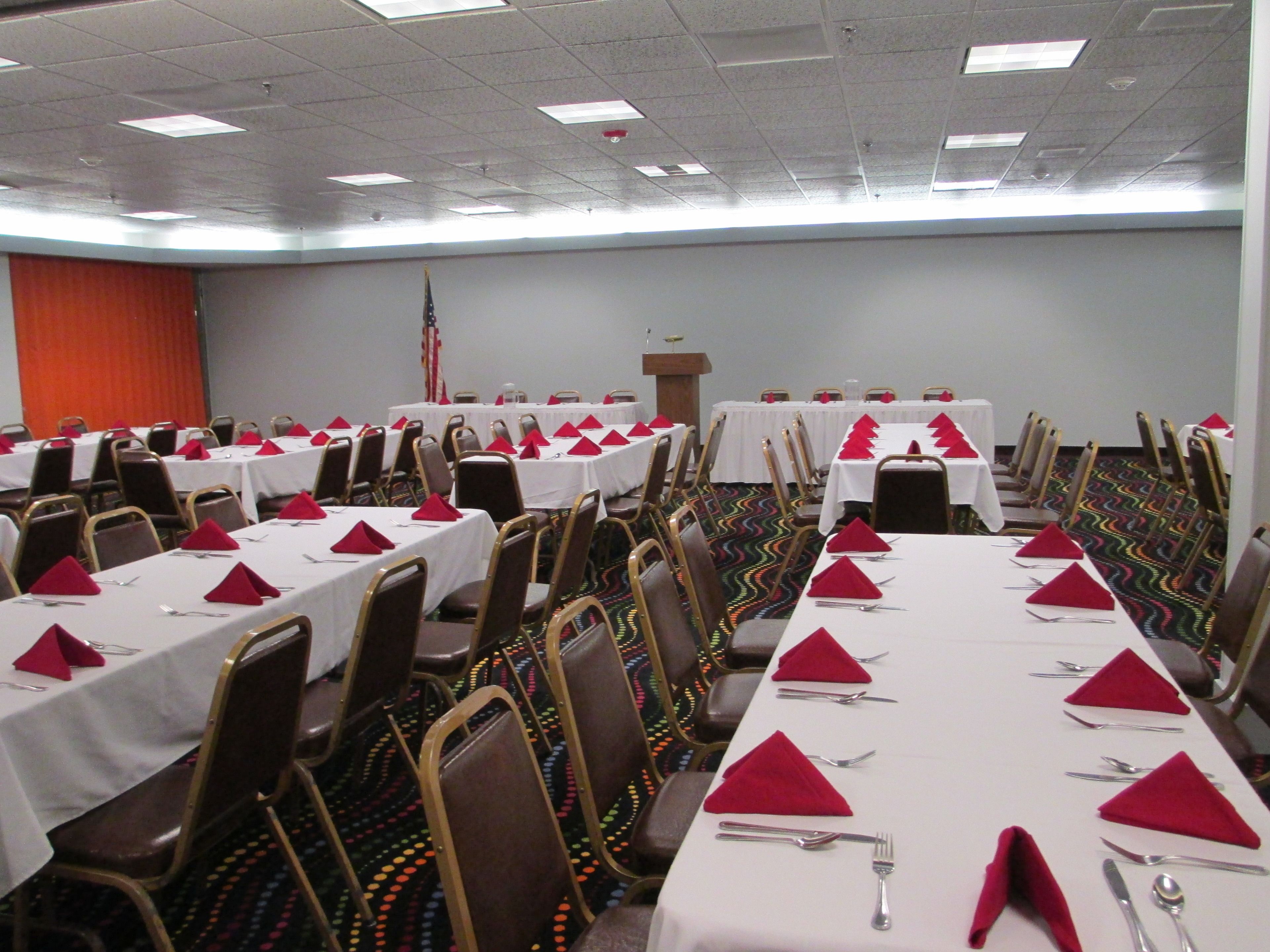 A conference room with multiple tables set for a meeting, equipped with chairs and tables.
