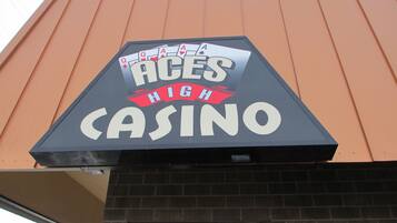A casino sign with the name "ACES HIGH CASINO" on a building with a brown facade.