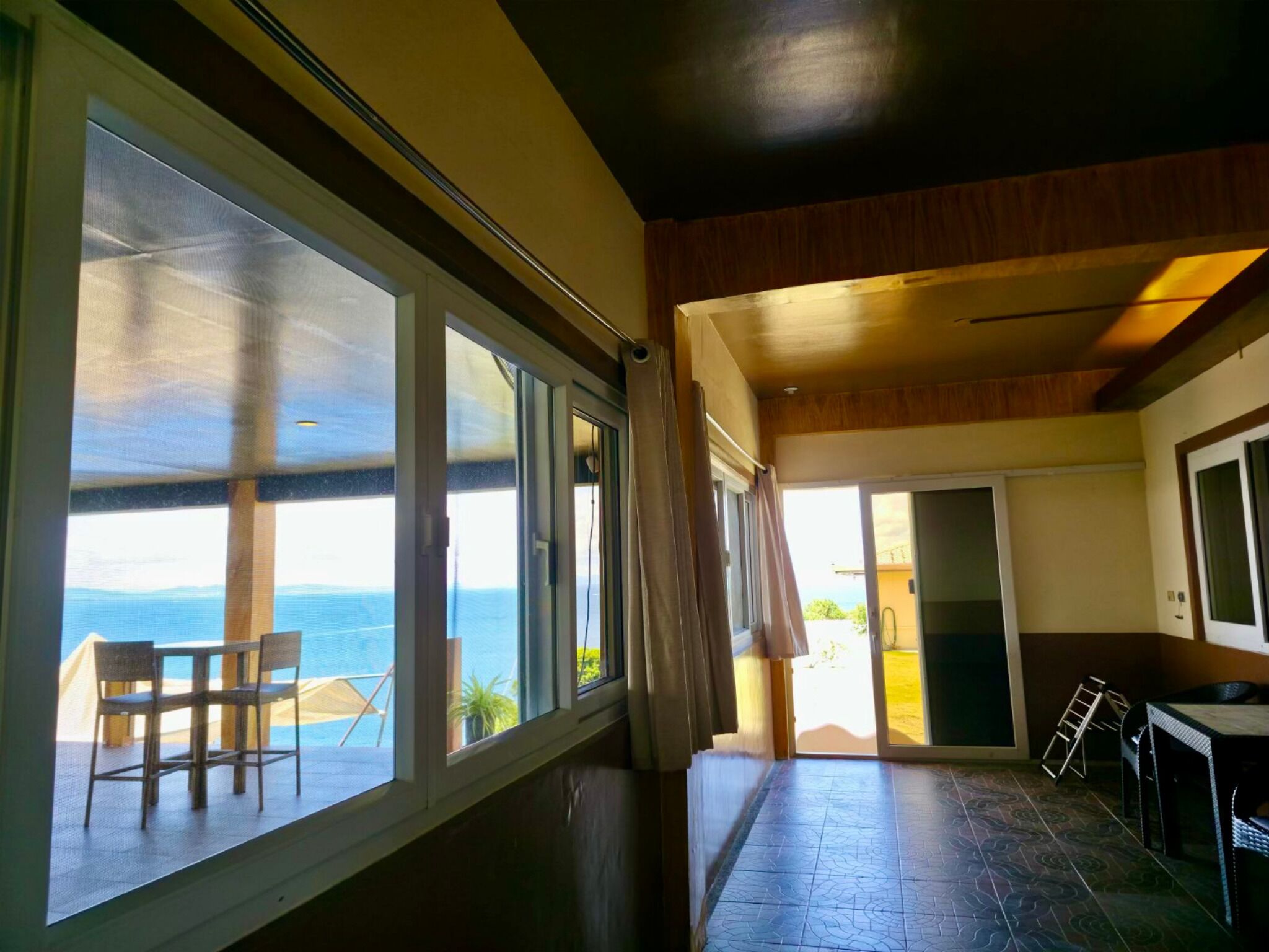 Una habitación con ventanas amplias, vistas al mar, zona de comedor con sillas y cocina.