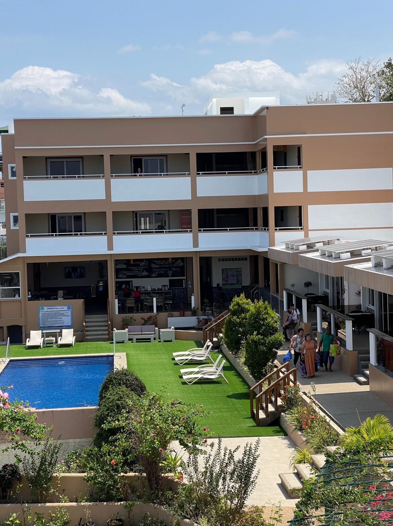 A multi-story hotel with a rooftop pool, outdoor seating, and a landscaped garden.