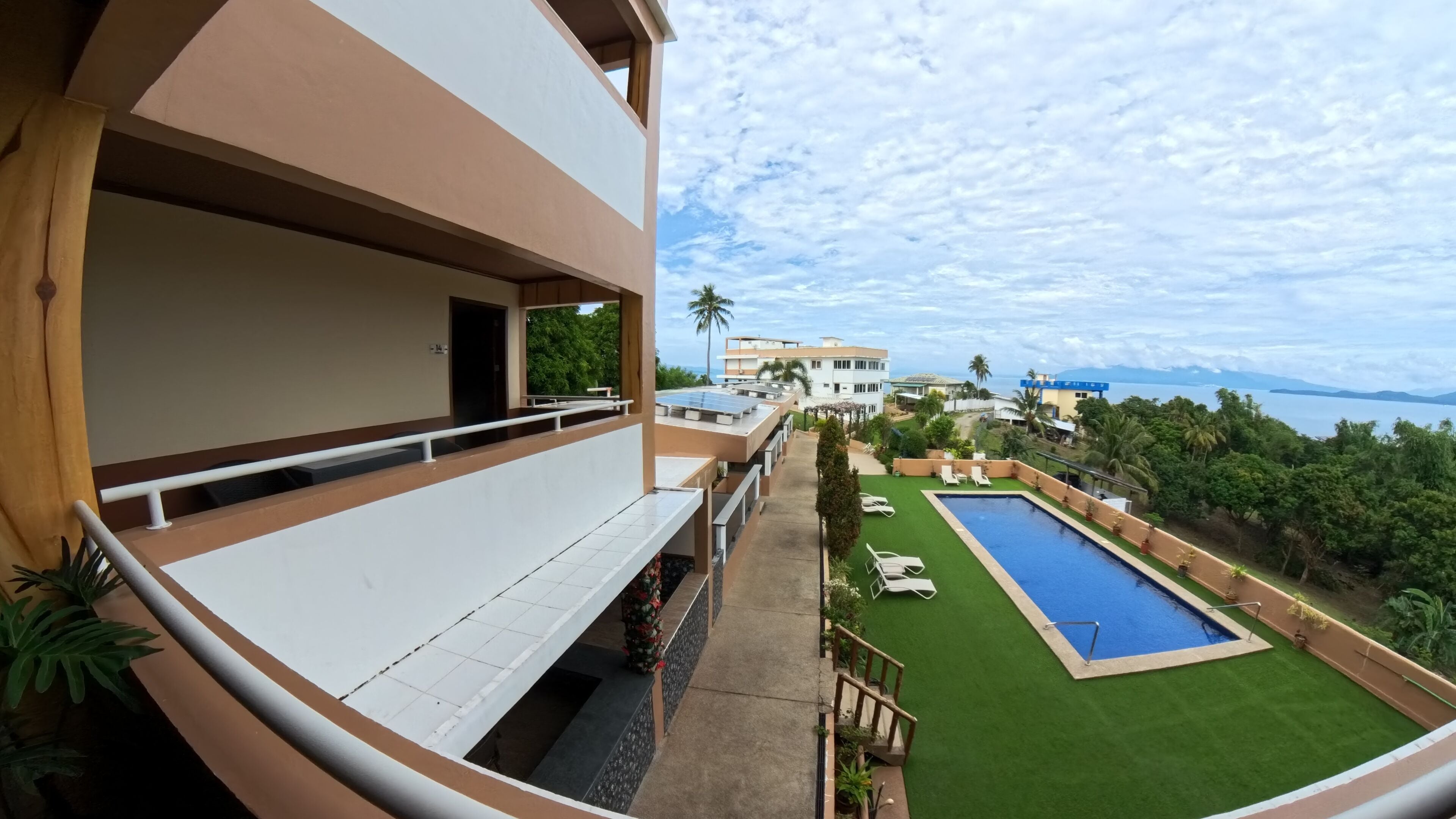 Un hotel con piscina en la azotea, césped verde y vista al mar.